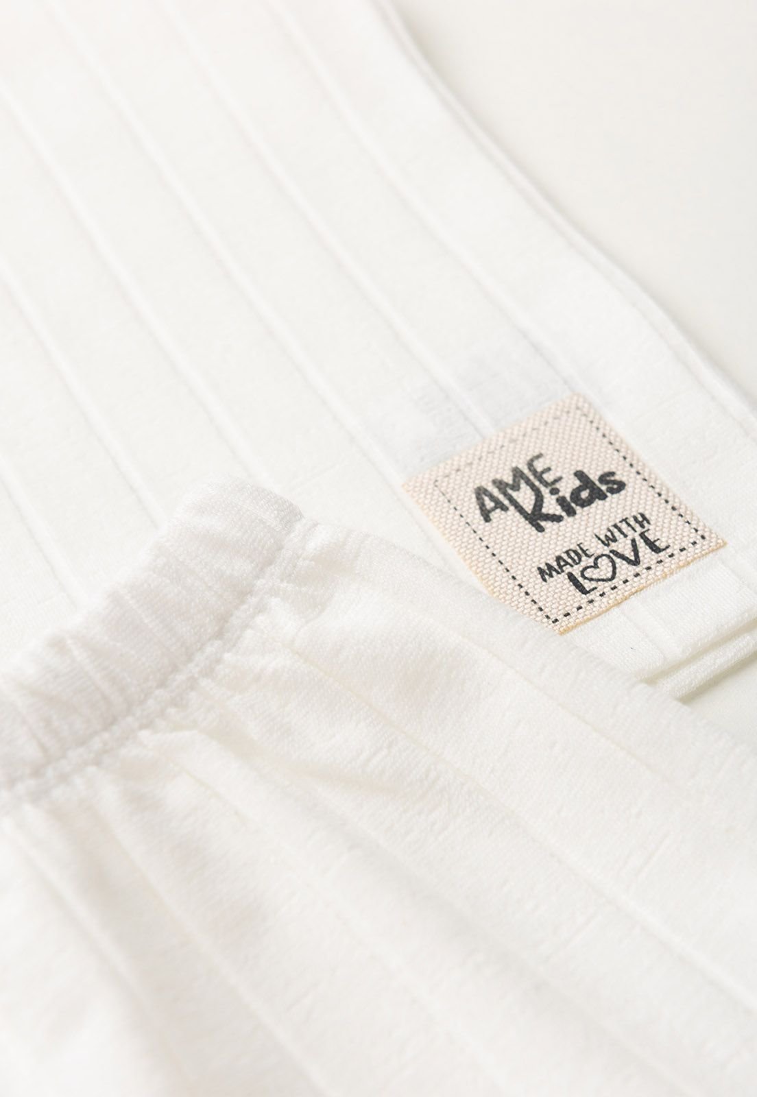 Detalhe: Etiqueta Ame Kids do Conjunto Regata e Shorts Milano Ame Kids, cor Off-white